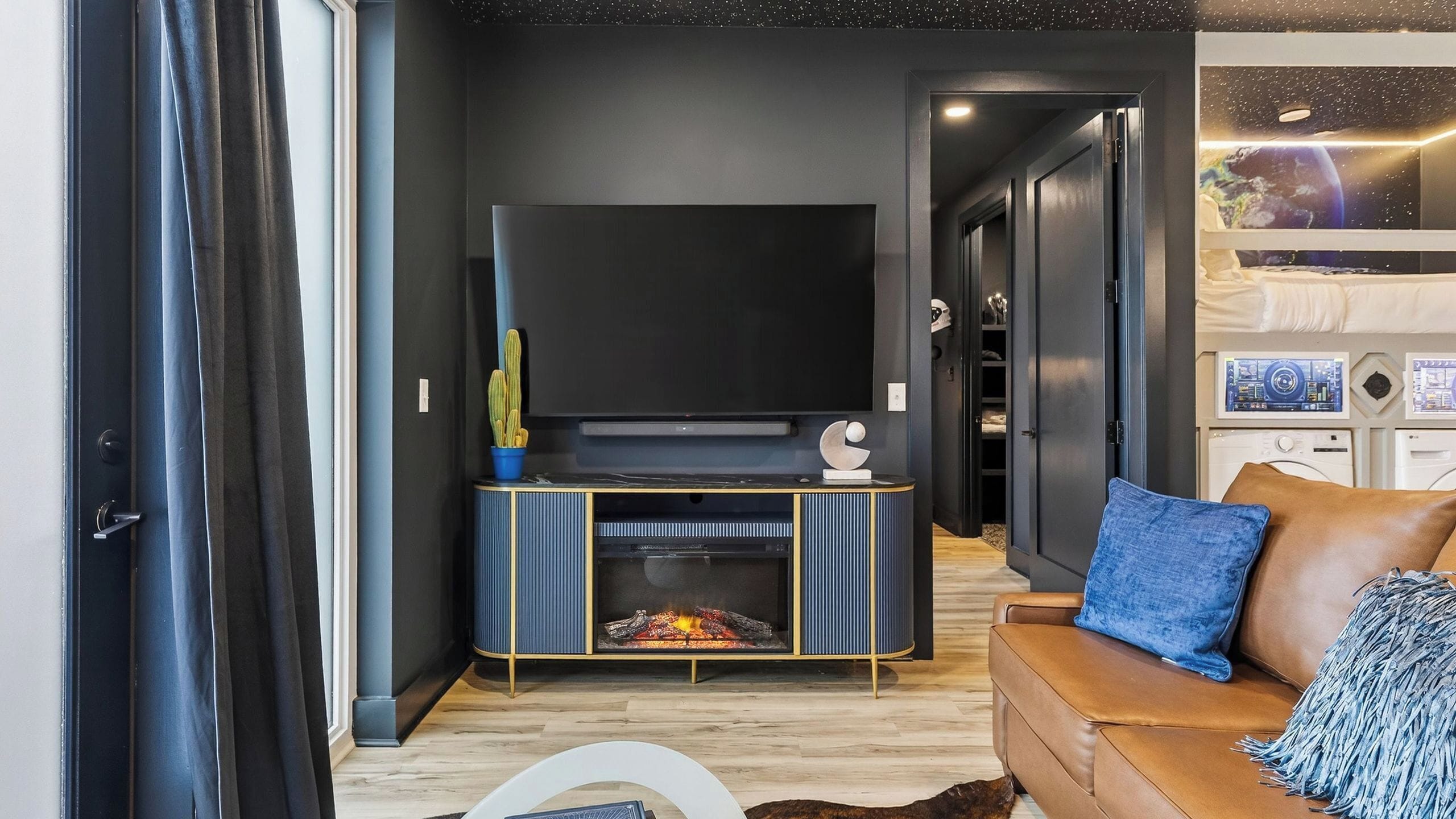 A modern living room with a flat-screen TV, a fireplace, and a leather sofa.