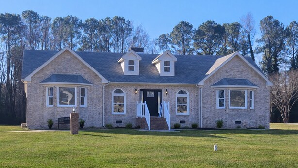 A two-story brick house with a front porch, a garage, and a well-maintained lawn. - Cozy 3-bedroom house in charming small town Sedley (Sedley)