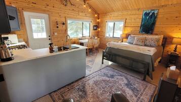 A cozy cabin interior with a kitchen, dining area, and a bed.