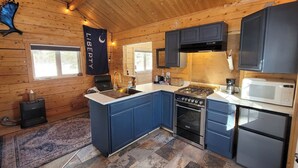 A modern kitchen with a central island, built-in appliances, and wooden walls.