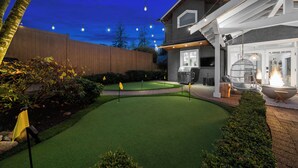 A well-maintained backyard with artificial grass, a barbecue area, and string lights. - SOWDEN HOUSE - Amazing & unique home located less than 20 minutes to down town. (North Vancouver)