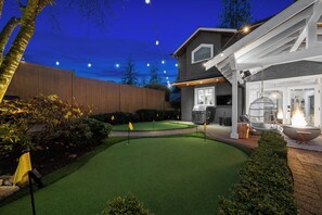 Un jardin bien entretenu, doté d’une pelouse artificielle, d’un espace barbecue et de guirlandes lumineuses.