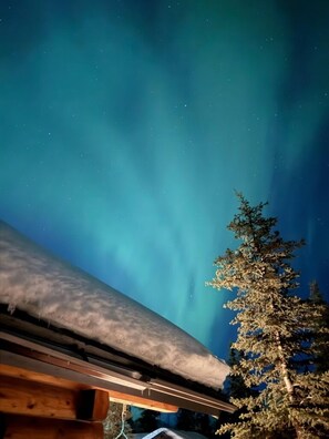 Una stanza con un'ampia finestra affacciata su un cielo notturno con aurore boreali visibili.
