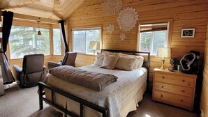 Een gezellig houten slaapkamer met een bed, een stoel, een nachtkastje en decoratieve wandversieringen.