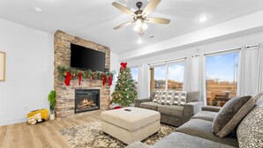 Een moderne woonkamer met een open haard, een kerstboom en grote ramen.