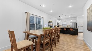 Een moderne keuken met houten vloer, witte wanden en een centraal eiland met barkrukken.