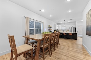 Cozinha moderna com piso de madeira, paredes brancas e uma ilha central com banquetas.