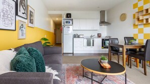 Ein modernes Wohnzimmer mit einem grauen Sofa, einem Couchtisch und einem Essbereich mit Holztisch und Stühlen.