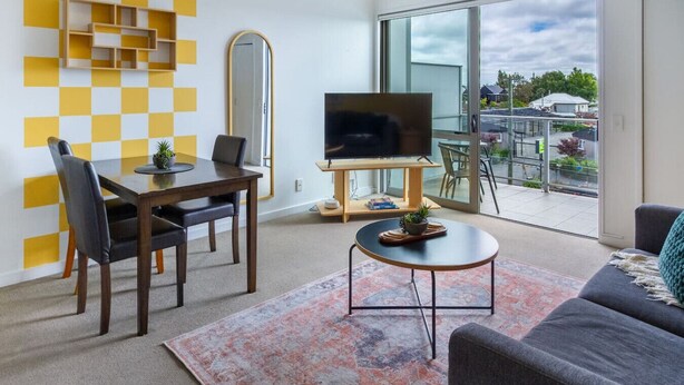 Ein modernes Wohnzimmer mit Essbereich, einem Flachbildfernseher und einem Balkon mit Aussicht.