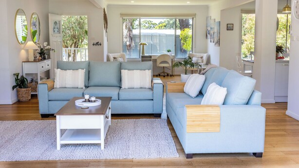 Ein geräumiges Wohnzimmer mit zwei hellblauen Sofas, einem Holztisch und einem weißen Teppich.