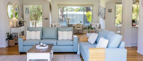 A spacious living room with two light blue sofas, a wooden coffee table, and a white rug.