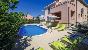 A pool area with lounge chairs and a building with balconies. - Awesome home in Kastel Luksic (Kastel Luksic)