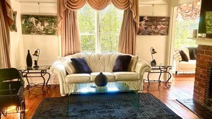 Un salón con un sofá blanco, un tapete estampado, una mesita y una silla.