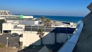 A building with a 'Glamour' sign, a parking area, and a view of the ocean. - MEDUSE - Studio Héliopolis C29 - Luxury - 2 people (AGDE)