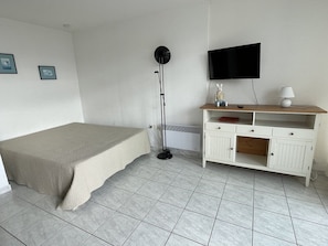 A bedroom with a bed, a TV mounted on the wall, a desk with drawers, and a floor lamp. - Studio Héliopolis C 36 - 4 people (AGDE)