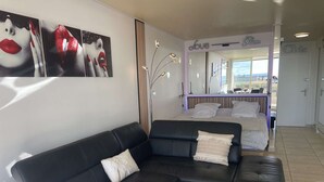 A modern hotel room with a black leather sofa, a bed with white linens, and a large mirror reflecting the room. - HOLIDAYS - Studio Héliopolis C 66 - Luxury - 2 people (AGDE)