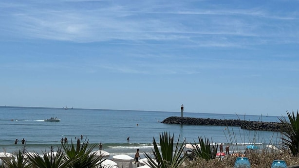 A beach with a lighthouse, calm sea, and people enjoying the water. - HOLIDAYS - Studio Héliopolis C 66 - Luxury - 2 people (AGDE)