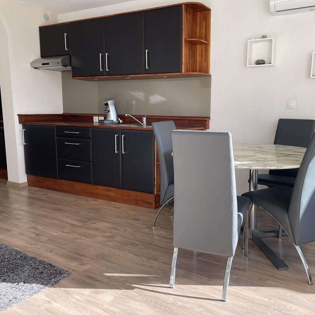 Moderni keittiö, jossa on mustat kaapit, puinen työtaso ja sisäänrakennettu liesi.