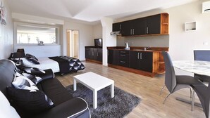 Ett kompakt bostadsutrymme med ett litet kök, en matplats och en sittgrupp med en soffa och ett soffbord.
