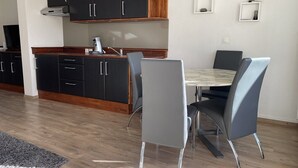 Ett modernt kök med mörka skåp, en bänkskiva i trä och en inbyggd spis. Det finns en matplats med ett bord och stolar.