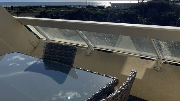 En balkong med fri utsikt över havet och stranden.