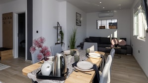 Zona pranzo moderna con tavolo in legno apparecchiato per due, runner decorativo bianco e nero e un vaso bianco e nero.
