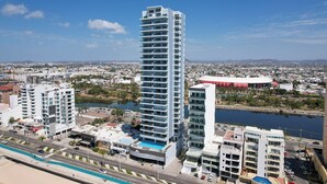 Un hotel moderno de gran altura con varias plantas, una piscina y vistas de la ciudad circundante.