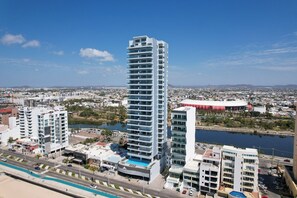 A high-rise hotel with multiple floors, a swimming pool, and a view of the surrounding cityscape. - Malecon Love (Mazatlán)