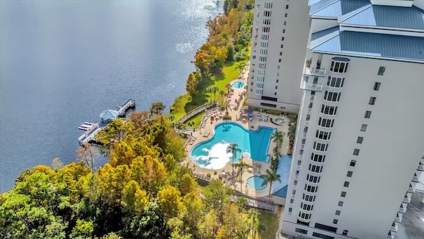 Ein Hochhaus-Hotel mit Swimmingpool, umgeben von üppiger Vegetation und einer Anlegestelle, die sich in ein Gewässer erstreckt.