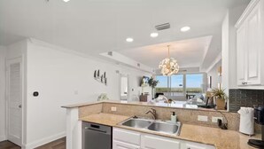 Eine moderne Küche mit weißen Schränken, Granit Arbeitsplatten und einem eingebauten Geschirrspüler.