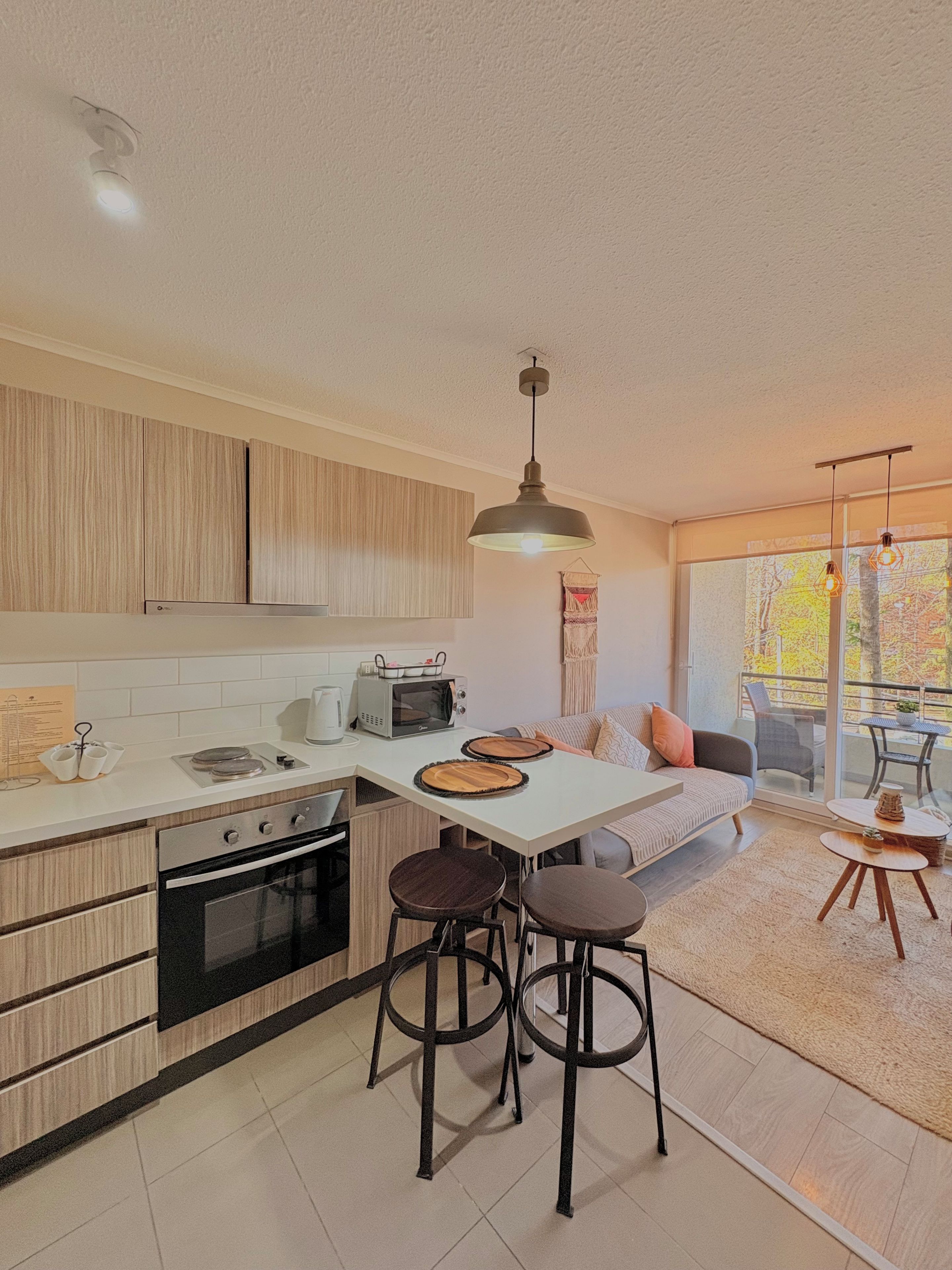 A modern kitchen with a central island, bar stools, and a dining area with a view.