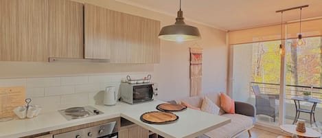 A modern kitchen with a central island, bar stools, and a dining area with a view.
