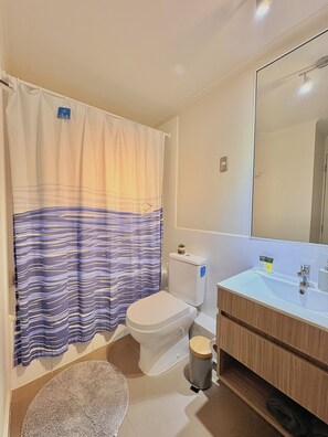 A bathroom with a toilet, sink, and shower curtain. - Lodge with a View of the Volcano | Wi-Fi + Heating (Pucon)