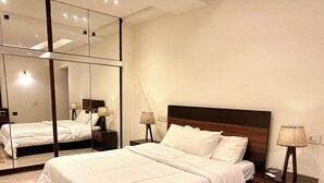 Une chambre à coucher moderne avec un grand lit, des tables de chevet, un miroir et un luminaire au plafond.