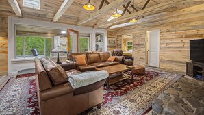 A log cabin interior with a leather sofa, a coffee table, a TV, and a fireplace.