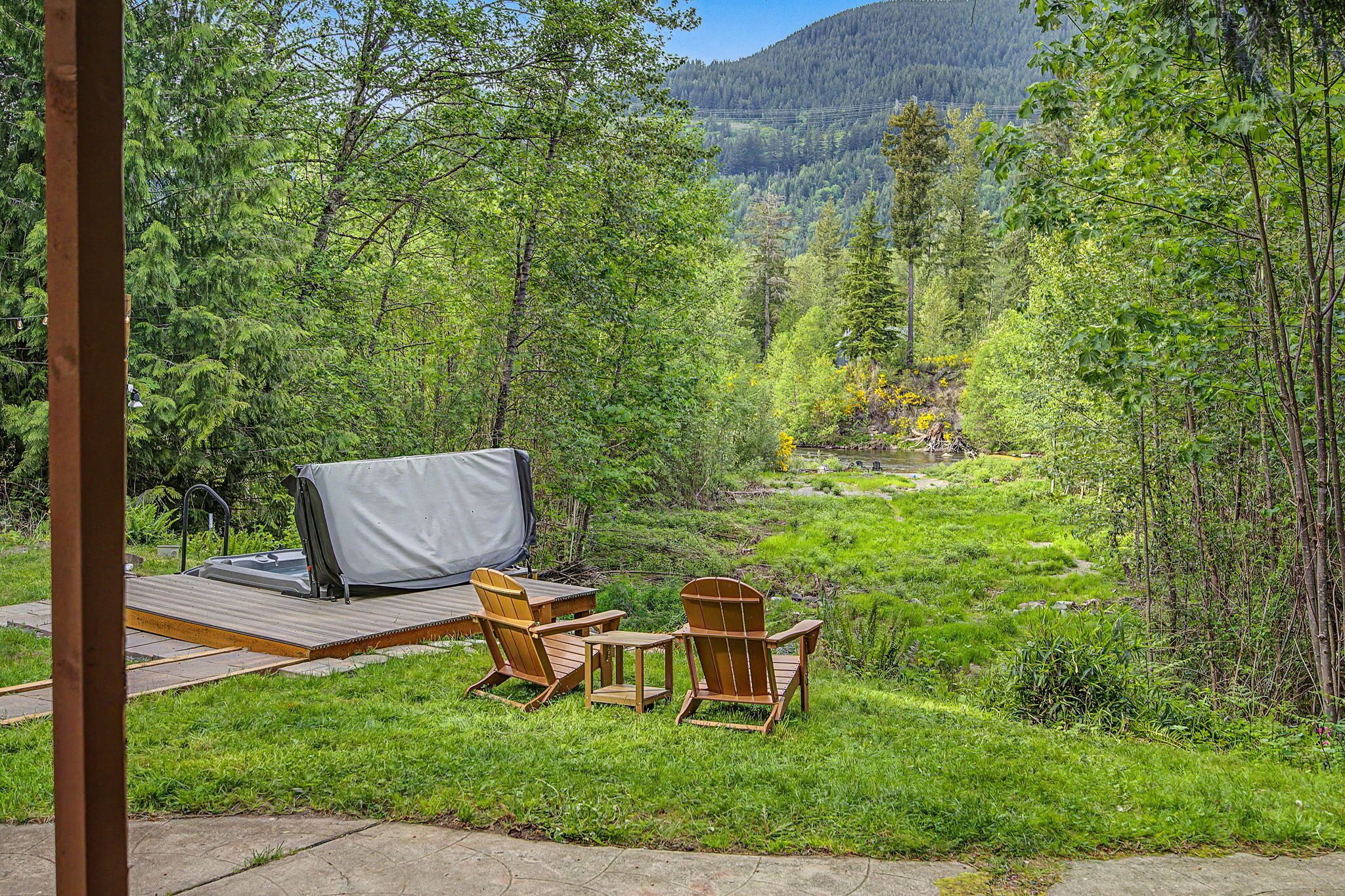 A deck with outdoor furniture, a covered grill, and a view of a forested valley.