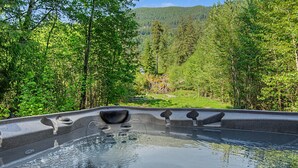 A hot tub with a view of a forested area and a mountain in the background.