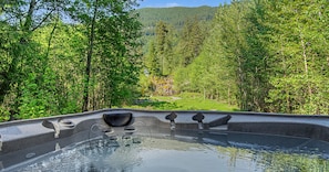 Un jacuzzi con vistas a una zona boscosa y una montaña al fondo.