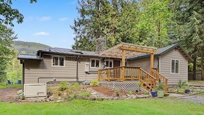 A two-story house with a wooden deck, a stone chimney, and a generator.