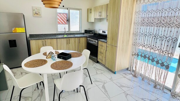 Una cucina moderna con zona pranzo, frigorifero, forno a microonde e piano cottura.