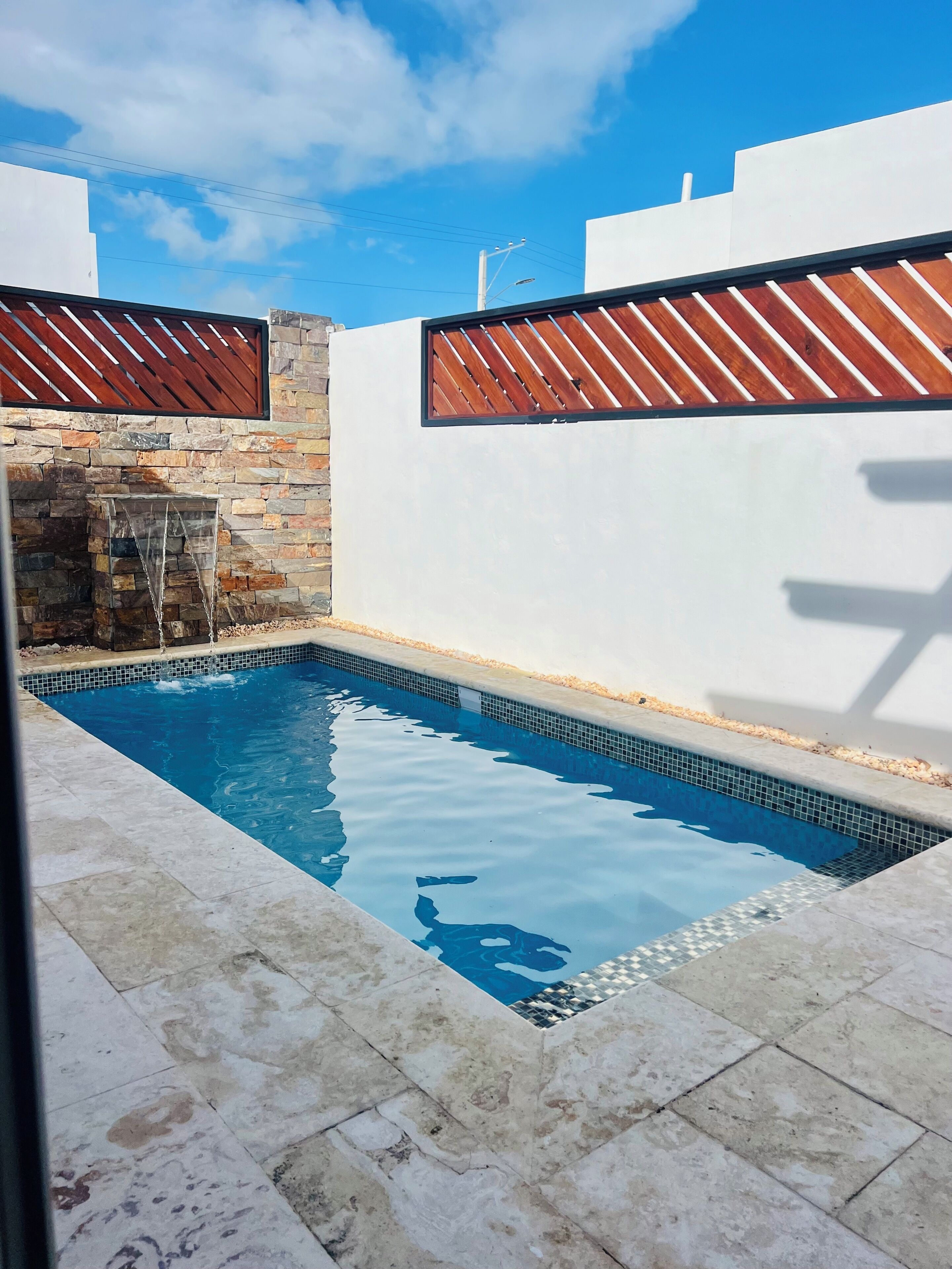 A swimming pool with stone walls and a tiled deck.