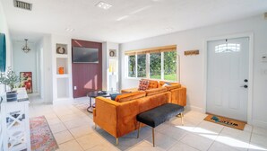A modern living room with a sofa, bench, and a television. - Spacious 7-bedroom house in delightful Southwest Ranches with AC (Southwest Ranches)