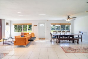 A spacious living room with a sofa, coffee table, and dining area with a table and chairs.