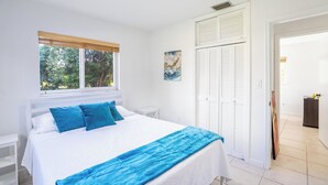 A bedroom with a bed, a window with blinds, a painting on the wall, and a door leading to another room. - Spacious 7-bedroom house in delightful Southwest Ranches with AC (Southwest Ranches)