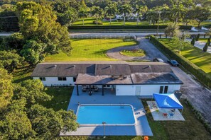 A house with a swimming pool, covered patio, and a fenced yard. - Spacious 7-bedroom house in delightful Southwest Ranches with AC (Southwest Ranches)