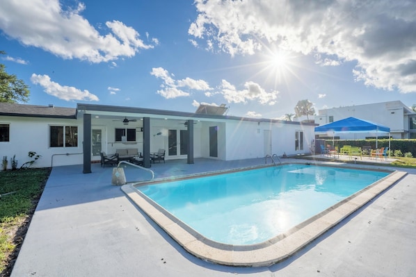 A swimming pool with a clear blue water, surrounded by a concrete deck.