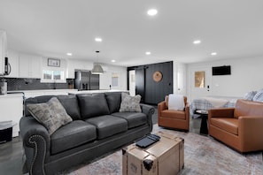 Ein modernes Wohnzimmer mit einem schwarzen Ledersofa, einem braunen Ledersessel und einem kleinen Beistelltisch.