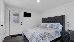Une chambre à coucher avec un lit, une table de chevet, une commode, une porte et une fenêtre.