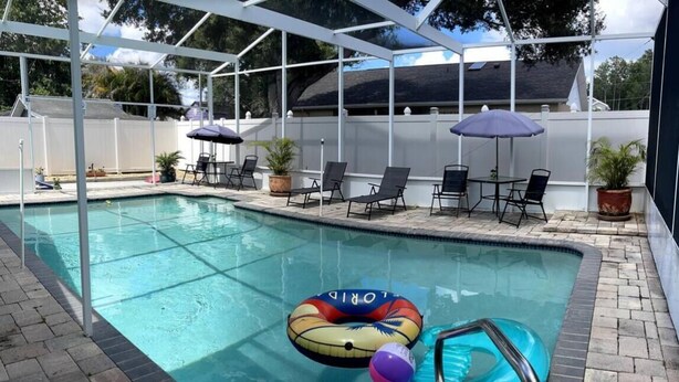 A swimming pool with lounge chairs and umbrellas, surrounded by a covered patio area. - Cozy 1-bedroom studio in perfect Tampa with AC (Tampa)
