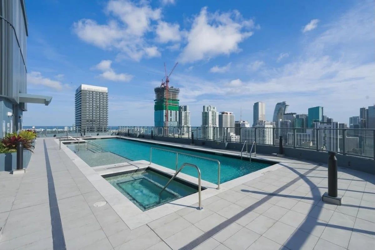 A rooftop swimming pool with a city skyline in the background.